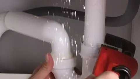 Pipe wrench tightening a leaking pipe joint
